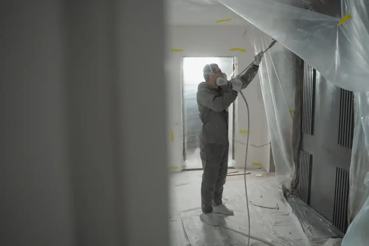 Texture applied with spray equipment and protective gear in an interior room